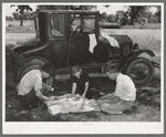 Migrant workers eating dinner by the side of their car while they are camped near Prague, Oklahoma