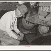 Father of migrant steeple-jack putting bolts in connecting rod while camped near Prague, Oklahoma. Lincoln County