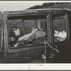 Migrant woman reaching in automobile for supplies while camped near Prague, Oklahoma. Lincoln County, Oklahoma