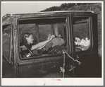 Migrant woman reaching in automobile for supplies while camped near Prague, Oklahoma. Lincoln County, Oklahoma
