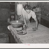 Daughter of agricultural day laborer cleaning up kitchen. Black spots on table cloth are flies. McIntosh County, Oklahoma