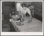 Daughter of agricultural day laborer cleaning up kitchen. Black spots on table cloth are flies. McIntosh County, Oklahoma