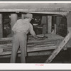 Cleaning screens used in grading at peanut-shelling plant. Comanche, Texas