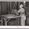 Workman removing cotton seed cake from mat after oil has been removed. The cake is removed by means of a mandrel machine. Cotton seed oil mill, McLennan County, Texas