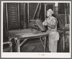 Workman removing cotton seed cake from mat after oil has been removed. The cake is removed by means of a mandrel machine. Cotton seed oil mill, McLennan County, Texas