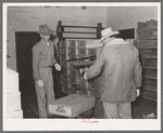 Weighing box of turkeys to be loaded into freight car at cold storage plant. Brownwood, Texas. Sheepskin coat is necessary because of low temperature in cold storage plant