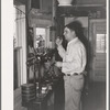 Man in office at stockyards. After cattle are sold at auction he calls out to the keepers in the pens to put cattle with certain numbers in certain pens. In this way each buyer's cattle are separated and delivery is facilitated