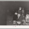 Group of men gathered around remains of fire at early morning vegetable market. San Angelo, Texas