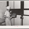 Removing tray of freshly baked bread from conveyor type oven. Bakery, San Angelo, Texas