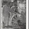 Negro farmer and blacksmith shop workman look over much-repaired wagon wheels to see if they can be made usable again. Depew, Oklahoma