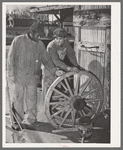 Negro farmer and blacksmith shop workman look over much-repaired wagon wheels to see if they can be made usable again. Depew, Oklahoma