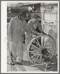 Negro farmer and blacksmith shop workman look over much-repaired wagon wheels to see if they can be made usable again. Depew, Oklahoma