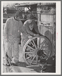 Negro farmer and blacksmith shop workman look over much-repaired wagon wheels to see if they can be made usable again. Depew, Oklahoma