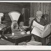 Farmer reading newspaper in feed and general produce store. Eufaula, Oklahoma