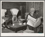 Farmer reading newspaper in feed and general produce store. Eufaula, Oklahoma