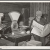 Farmer reading newspaper in feed and general produce store. Eufaula, Oklahoma