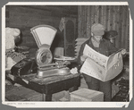 Farmer reading newspaper in feed and general produce store. Eufaula, Oklahoma