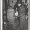 Putting coal in the stove at pie supper in Muskogee County, Oklahoma. See general caption number 24