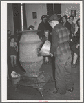 Putting coal in the stove at pie supper in Muskogee County, Oklahoma. See general caption number 24