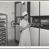 Putting loaves of bread into conveyor type oven for baking. Bakery, San Angelo, Texas