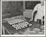 Brushing top of rolls with melted grease so that they will brown. Bakery, San Angelo, Texas
