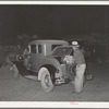Farmer putting vegetables in rear of car at early morning vegetable market. San Angelo, Texas