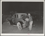Farmer putting vegetables in rear of car at early morning vegetable market. San Angelo, Texas