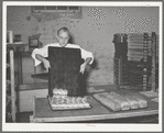 Removing rolls from tray at bakery. San Angelo, Texas