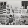 Placing packaged goods on display rack. Retail grocery, San Angelo, Texas