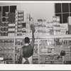 Placing packaged goods on display rack. Retail grocery, San Angelo, Texas