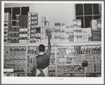 Placing packaged goods on display rack. Retail grocery, San Angelo, Texas