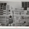 Placing packaged goods on display rack. Retail grocery, San Angelo, Texas