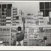 Placing packaged goods on display rack. Retail grocery, San Angelo, Texas