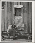 Pomp Hall, Negro tenant farmer, repairing piece of tin which covers window of his house. Creek County, Oklahoma