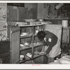 Removing plates from kitchen cupboard in home of Pomp Hall, Negro tenant farmer. Creek County, Oklahoma