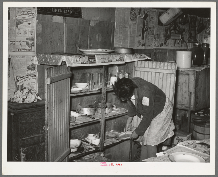 Removing plates from kitchen cupboard in home of Pomp Hall, Negro ...