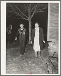 Couple coming around the corner of the house while playing the game, "Fishing for love," at play party in McIntosh County, Oklahoma. See general caption number 26