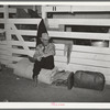 Cattlemen sitting on rolled up camp bed in cattle bed in cattle barns at the San Angelo Fat Stock Show, San Angelo, Texas