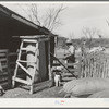 Corner of goat shearing pen with partly filled bag of mohair and filled bags. Ranchman is counting goats as they leave the shearing pen. Kimble County, Texas