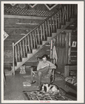 Manager of the Navajo Lodge with his dog before the fireplace on a snowy afternoon. Datil, New Mexico