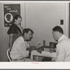 Doctor at clinic taking case history of agricultural worker. Agua Fria migratory labor camp. Arizona