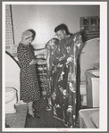 Member of the United Producers and Consumers Cooperative looking at a shower curtain displayed by salesman in the household equipment department. Phoenix, Arizona