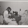 Wife of migratory agricultural laborer sewing at the Aqua Fria migratory labor camp, Arizona. These machines are rented for a nominal sum which remains in the camp fund to be used as the camp committee decides