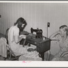 Wife of migratory agricultural laborer sewing at the Aqua Fria migratory labor camp, Arizona. These machines are rented for a nominal sum which remains in the camp fund to be used as the camp committee decides