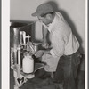 Member of the Arizona part-time farms, Chandler Unit, filling milk bottles in the dairy of the farm. Maricopa County, Arizona