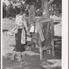 Mrs. Faro Caudill placing milk into homemade cooling box. Damp cloths are wrapped around buckets and jars of milk, and rapid evaporation in the open air produces sufficient cooling to keep milk. Pie Town, New Mexico
