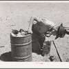Syphoning gas from storage container to use in truck-tractor. Pie Town, New Mexico