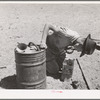 Syphoning gas from storage container to use in truck-tractor. Pie Town, New Mexico