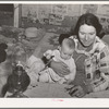 Mrs. Holley holding her baby while playing forty-two at party after literary society meeting. Pie Town, New Mexico. Mrs. Holley and her husband farmed in Texas before homesteading in Pie Town, New Mexico