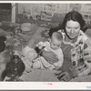 Mrs. Holley holding her baby while playing Fforty-two at party after literary society meeting. Pie Town, New Mexico. Mrs. Holley and her husband farmed in Texas before homesteading in Pie Town, New Mexico